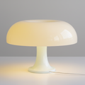 Lampe à poser iconique en polycarbonate blanc translucide, design champignon rétro des années 70, offrant une lumière d'ambiance chaleureuse pour intérieur vintage ou moderne.