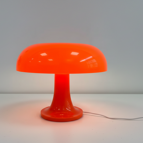 Lampe à poser iconique en polycarbonate orange translucide, design champignon rétro des années 70, offrant une lumière d'ambiance chaleureuse pour intérieur vintage ou moderne.