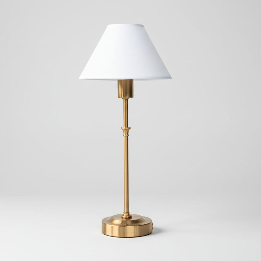 Lampe à poser élégante avec pied fin en laiton doré et abat-jour conique blanc, luminaire de style classique et raffiné pour table de chevet ou console d'entrée.
