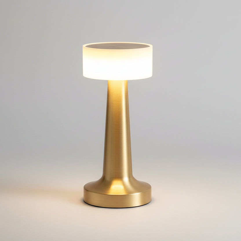 Lampe de table LED rechargeable sans fil en laiton doré brossé, dotée d'un abat-jour cylindrique lumineux et d'un pied conique élégant, idéale pour une ambiance tamisée en restaurant ou sur une table de chevet.