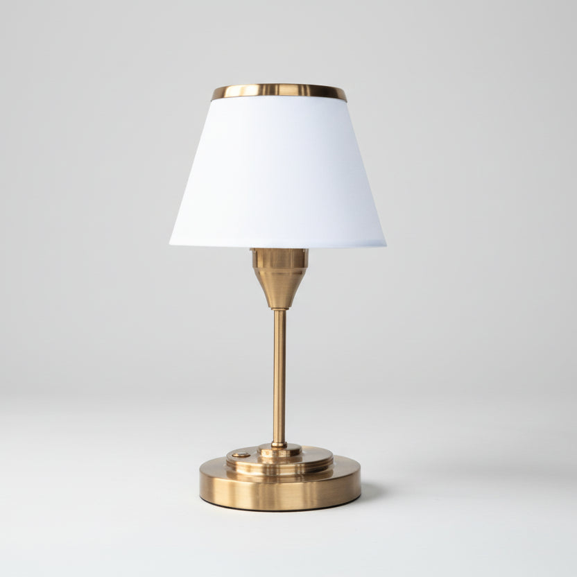 Lampe de table LED rechargeable sans fil avec pied fin en laiton doré et abat-jour conique blanc bordé de métal, luminaire élégant pour restaurant ou table de chevet.