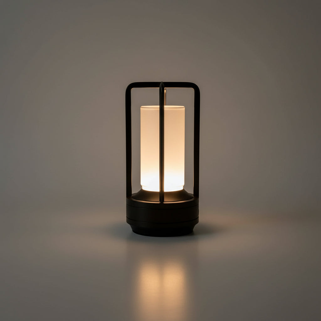 Lampe lanterne LED sans fil haut de gamme avec diffuseur en verre cylindrique et structure minimaliste en laiton noir, luminaire rechargeable pour ambiance luxueuse en intérieur ou extérieur abrité.